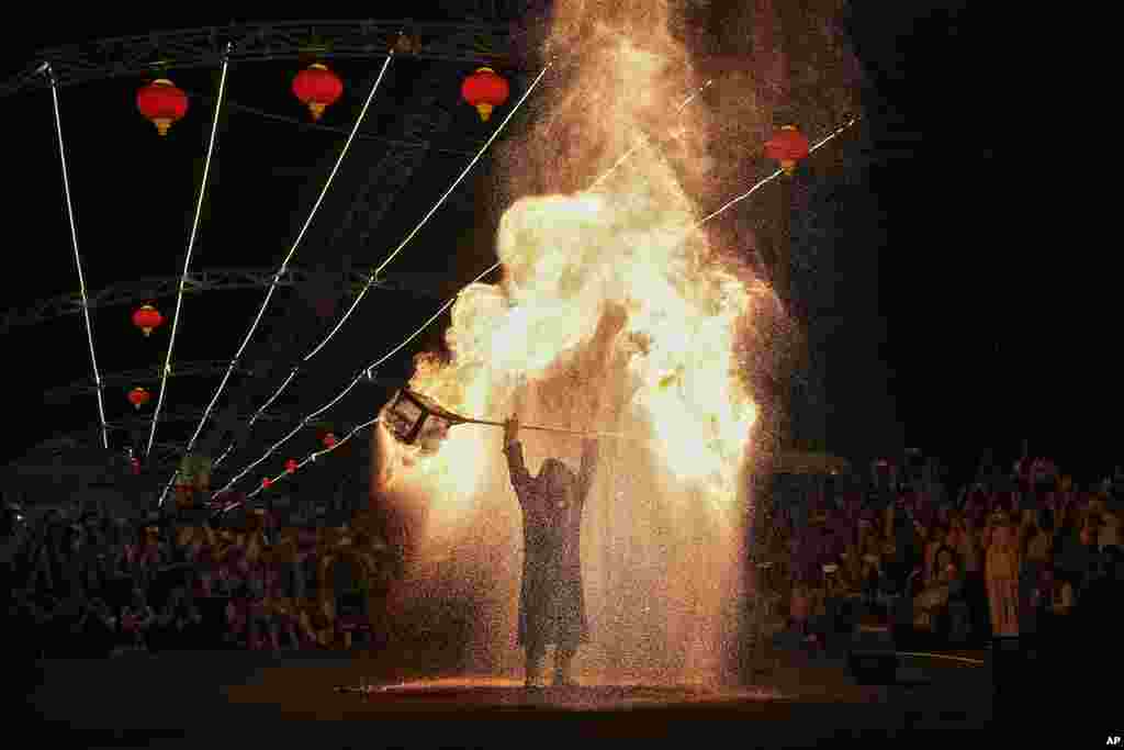 People watch an artist performs a fire kettle show during the Mid-Autumn Festival at a night market in Beijing.