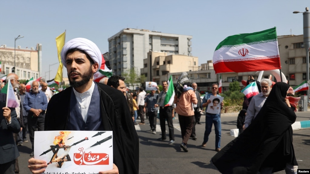 在伊朗首都德黑兰，一名伊朗神职人员在反以色列集会上手持反以色列海报。（2024年4月19日）(photo:VOA)
