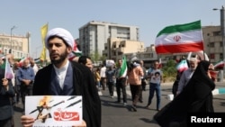 在伊朗首都德黑蘭，一名伊朗神職人員在反以色列集會上手持反以色列海報。（2024年4月19日）