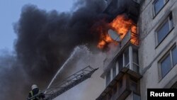 Firefighters work to put out a fire in a residential apartment building after it was hit by shelling in Kyiv