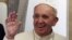 FILE - Pope Francis waves during the media's meeting aboard the papal plane while en route to Rome, Italy, Nov. 30, 2015.