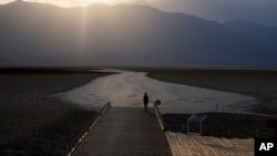 A person walks on a boardwalk at the salt flats at Badwater Basin, Aug. 17, 2020, in Death Valley National Park, Calif. Death Valley recorded a scorching 130 degrees (54.4 degrees Celsius).