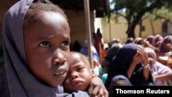 FILE PHOTO: Internally displaced Somali girl carries her sibling as they wait to collect food relief from the WFP at a settlement in the capital Mogadishu