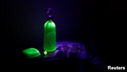 A Pernod opalex ashtray, a 1950's Gablonz Uranium Glass ring and a 1940's Uranium Glass soda siphon, glow under ultraviolet light in Wangen an der Aare, Switzerland, Jan. 23, 2018.
