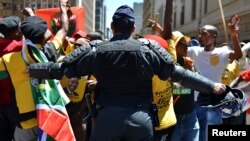 A police officer tries to control ANC supporters as they attempt to confront members of the opposition Democratic Alliance party marching in central Johannesburg, Feb. 12, 2014. 