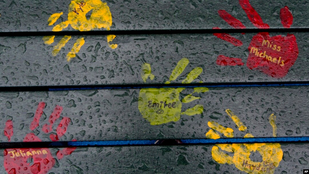 Cat telapak tangan dengan nama-nama guru dan murid yang tewas dalam penembakan tahun 2012, di atas bangku taman di Sekolah Dasar Sandy Hook, Newtown, Connecticut.