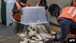 Un responsable d'un bureau de vote vide une urne pleine de bulletins de vote à la fin du vote à l'école secondaire Matero de Lusaka, le 12 août 2021.