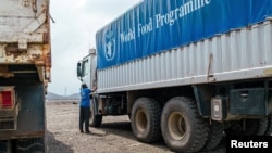 FILE - A WFP worker stands next to a truck carrying aid from Port Sudan to Darfur and other famine-stricken parts of Sudan, Nov. 12, 2024. (WFP/Abubakar Garelnabei/Handout via Reuters)