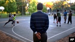 FILE - Abdirizak Bihi, right, executive director of the Somali Education and Social Advocacy Center, watches kids play basketball at Currie Park in Minneapolis, near a large Somali community in the Cedar Riverside neighborhood, Sept. 22, 2014.