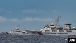 Kapal Penjaga Pantai China (kanan) terlihat melewati kapal Penjaga Pantai Filipina BRP Cape Engaño (kiri), seperti yang difoto dari BRP Cabra selama misi pasokan ke Sabina Shoal di perairan yang disengketakan di Laut Cina Selatan, 26 Agustus 2024. (Jam Sta Rosa / AFP)