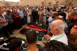 FILE - Mourners pray for fighters killed in airstrikes by warplanes of General Khalifa Haftar's forces, in Tripoli, Libya, April 24, 2019.