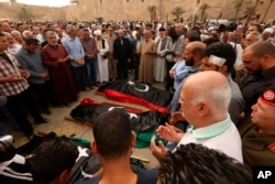 FILE - Mourners pray for fighters killed in airstrikes by warplanes of General Khalifa Haftar's forces, in Tripoli, Libya, April 24, 2019.