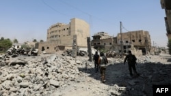 FILE - Fighters from the Syrian Democratic Forces (SDF), a U.S.-backed Kurdish-Arab alliance, walk through the rubble in an eastern area of the embattled city of Raqqa in northern Syria, Aug. 15, 2017.