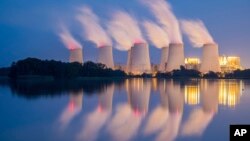 FILE - In this Sept. 19, 2018 photo steam and cooling towers of a lignite power plant are reflected in a pond in Peitz, eastern Germany. 