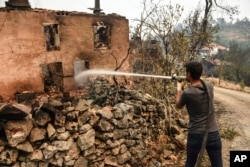 A man extinguishes a fire in his house in Semir village, near Manavgat, Antalya, Turkey, Aug. 3, 2021.