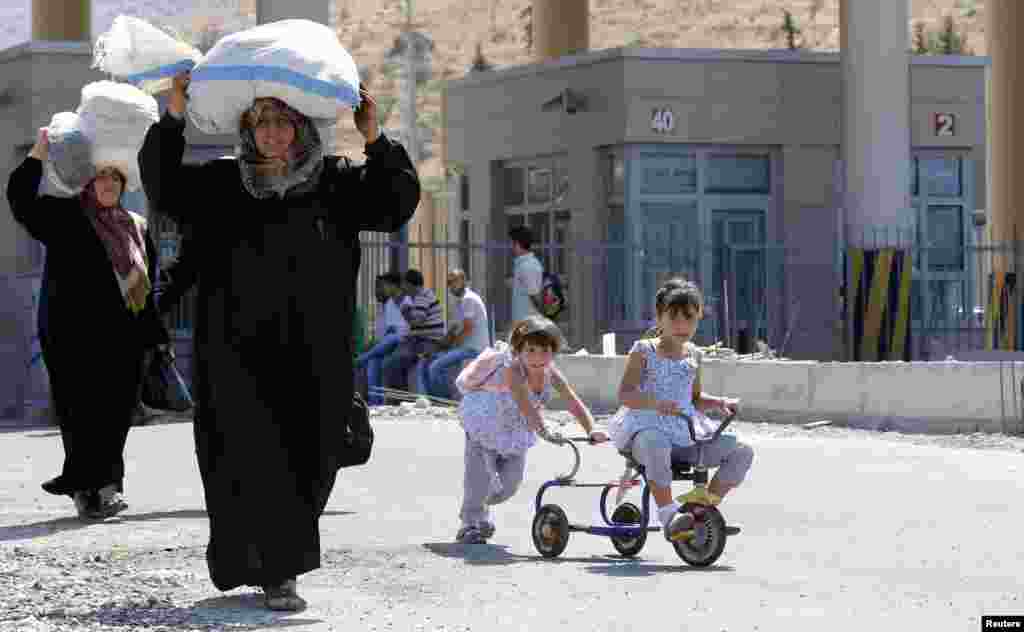 Syrian people carry their belongings as they enter Turkey at Cilvegozu, Sept. 4, 2013.