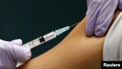 FILE - A medical worker receives a shot at a hospital in Tokyo.