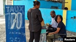 A woman exchanges dollars for Congolese francs at a street side exchange stall in Avenue du 24 Novembre, in Lingwala Municipality, Kinshasa, Democratic Republic of the Congo, July 26, 2017.