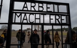 FILE - Visitors walk past the gate, inscribed with the words "Arbeit Macht Frei" (Work makes you free), of the former Sachsenhausen concentration camp, now a memorial, in Oranienburg, Feb. 7, 2020.