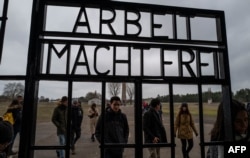 FILE - Visitors walk past the gate, inscribed with the words "Arbeit Macht Frei" (Work makes you free), of the former Sachsenhausen concentration camp, now a memorial, in Oranienburg, Feb. 7, 2020.