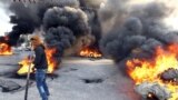 A protester walks in front of burning tires as they block a street in Libya&#39;s second city of Benghazi after the killings of two policemen. The fatal shootings of the two officers came just a day after the U.N. mission in Libya voiced &quot;deep concern&quot; over the near-daily violence plaguing the North African country, particularly the east.
