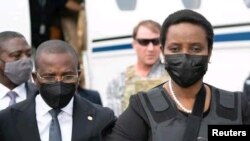 হাইতি বিমানবন্দরে অন্তর্বর্তীকালীন প্রধানমন্ত্রী ক্লাউড জোসেফ, নিহত প্রেসিডেন্ট জোভেনেল ময়েস'র স্ত্রী, মার্টিন ময়েসকে স্বাগত জানানোর পর তারা হেটে যাচ্ছেন 