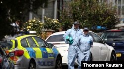 FILE - Forensic officers check for evidence in the street where a heavily pregnant woman was stabbed to death in the Thornton Heath area of London, June 30, 2019. 