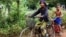 Im Chaem, a former Khmer Rouge cadre, is riding a bike along with her grandson in Anlong Veng, in Oddar Meanchey province in Cambodia, Sunday April 23, 2017. (Sun Narin/VOA Khmer)