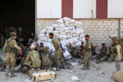 Turkish soldiers and Turkish-backed Syrian rebels gather near the Syrian border town of Ras al-Ayn, Oct. 12, 2019, as Turkey and its allies continued their assault on Kurdish-held border towns in northeastern Syria.