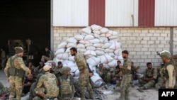 Turkish soldiers and Turkish-backed Syrian rebels gather near the Syrian border town of Ras al-Ayn, Oct. 12, 2019, as Turkey and its allies continued their assault on Kurdish-held border towns in northeastern Syria.
