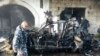 Petugas polisi Keamanan Dalam Negeri Lebanon berjalan melewati mobil yang rusak di lokasi ledakan di Hermel, 16 Januari 2014. 