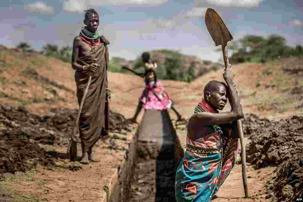 Members of the Turkana community work to unblock an irrigation canal to provide water to their sorghum crops in an arid dry area in Nanyee, near Lodwar, Turkana County, Kenya.