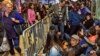 A woman (L) walks past as customers wait in line to buy the newly released iPhone 6 and iPhone 6 Plus, on the first day of sales outside the Apple store at Grand Central Terminal in New York, Sept.19, 2014.