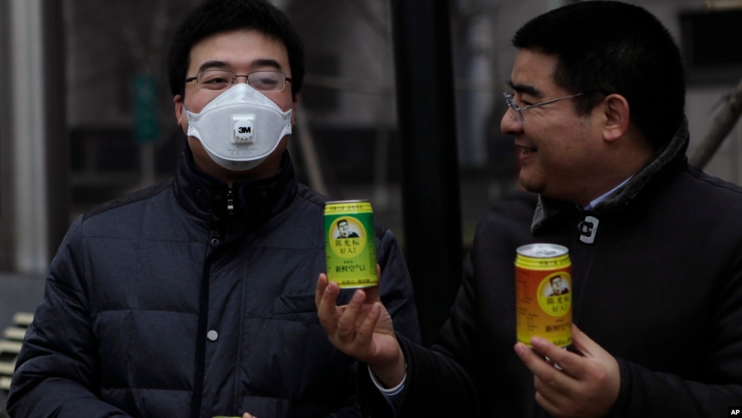 Multimiliuner Tiongkok, Chen Guangbiao (kanan) memberikan udara bersih kalengan pada seorang pria yang memakai masker udara karena polusi yang parah di Beijing (30/1). (Reuters/Barry Huang)