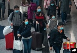 Passengers wear protective face masks arrive at the high speed train station in Hong Kong, Jan. 28, 2020. Hong Kong's leader has announced that all rail links to mainland China will be cut starting Friday.