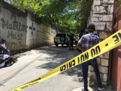 FILE - Journalists stand next to a yellow police cordon near the residence of Haiti's President Jovenel Moise after he was shot dead by unidentified attackers, in Port-au-Prince, July 7, 2021.