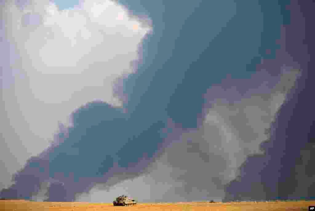 Israeli airstrikes pummel a wide range of targets in the Gaza Strip; an Israeli tank is seen here while heavy smoke rises from Gaza, July 22, 2014.&nbsp;