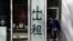 In this April 13, 2020, photo, a man looks at a shuttered shop lot displaying a sign that reads: 'For rent' at a commercial office building in Beijing.
