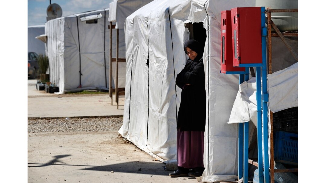 A Syrian displaced woman stands at the entrance of her tent at a refugee camp, in Bar Elias, in eastern Lebanon's Bekaa valley, March 5, 2021.