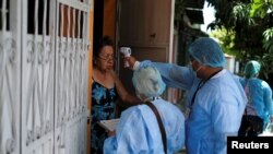 Un trabajador sanitario verifica la temperatura de un residente durante una campaña médica casa por casa mientras realizan un seguimiento de contactos en medio del brote del COVID-19 en Soyapango, El Salvador, 3 de julio de 2020.