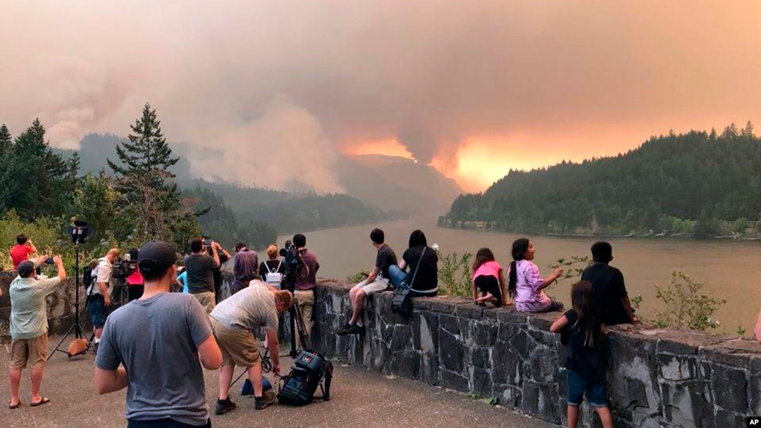 This photo, provided by Inciweb, shows people at a viewpoint overlooking the Columbia River watching the Eagle Creek wildfire burning in the Columbia River Gorge east of Portland, Ore., Sept. 4, 2017. A lengthy stretch of highway Interstate 84 remains closed as crews battle the growing Eagle Creek wildfire that has also caused evacuations and sparked blazes across the Columbia River in Washington state.