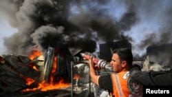 A Palestinian firefighter participates in efforts to put out a fire at a sponge factory after it was hit by Israeli artillery shells, according to witnesses, in the northern Gaza Strip, May 17, 2021.