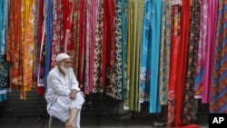 A man selling fabric waits for customers at a roadside stall in Lahore, Pakistan, September 25, 2011.