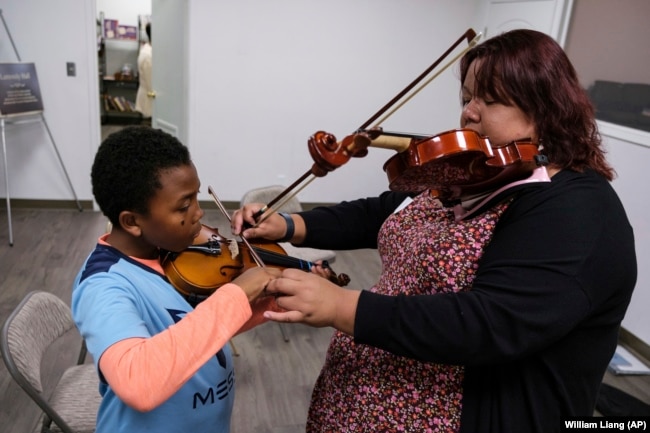 Johnathan Nealy, left, learns how to play the violin as part of an initiative that aims to promote equity in classical music at New Hope Presbyterian Church on Wednesday, Oct. 16, 2024, in Anaheim, California. (AP Photo/William Liang)