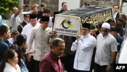 Mantan presiden RI Susilo Bambang Yudhoyono (kiri) berjalan di samping peti jenazah istrinya, Ibu Ani Yudhoyono, yang wafat di Singapura, Sabtu, 1 Juni 2019. (Foto: Roslan Rahman/AFP)