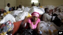 Election volunteers sit on bags containing ballots as they wait for tally sheets to be computed at the Fikin compilation center in Kinshasa, Democratic Republic of Congo, Thursday, Dec. 1, 2011.