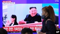 Una mujer pasa en frente de una pantalla de televisión en la estación de trenes de Seúl, donde se ve la imagen del líder norcoreano Kim Jong Un y su hermana Kim Yo Jong, el sábado 2 de mayo de 2020.