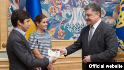 President Petro Poroshenko (R) hands a Ukrainian passport to Vladimir Fedorin as Maria Gaidar looks on, at a ceremony in Kyiv, Ukraine, August 4, 2015. (Photo source - president.gov.ua)