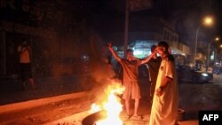 FILE - Libyan youth block a road with burning tires as they protest the poor public services and living conditions, in Libya's eastern coastal city of Benghazi, Sept. 12, 2020.