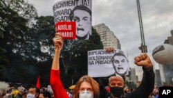 Demonstrators hold signs that read in Portuguese, "Impeachment now! Bolsonaro in prison," during a protest against Brazilian President Jair Bolsonaro and his handling of the COVID-19 pandemic, on Paulista Avenue in Sao Paulo, Brazil, June 19, 2021.